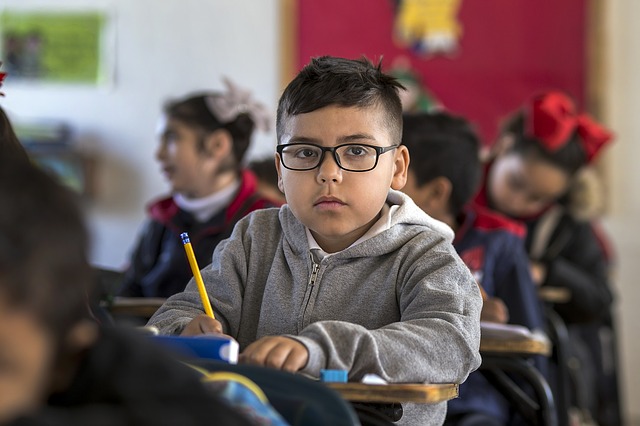 Niño pequeño con anteojos en aula de clase
